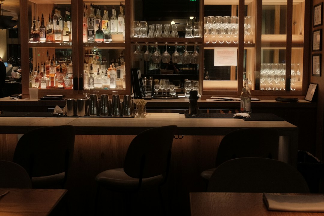 A dimly lit bar with bottles and glasses on shelves
