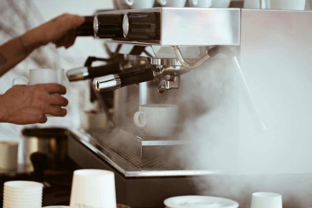 person holding white mug brewing coffee