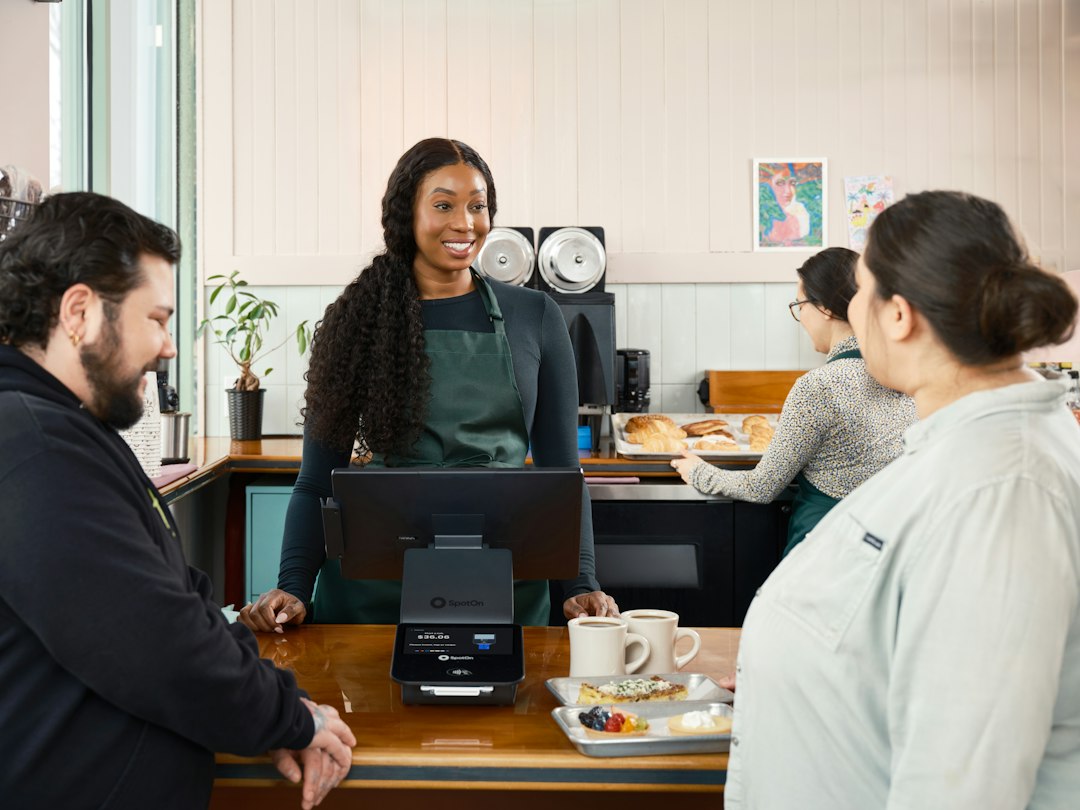A smiling woman serves customers at a cafe counter