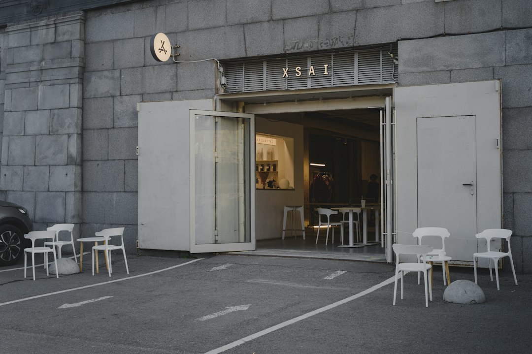 White chairs and small tables outside a cafe entrance with XSAI signage