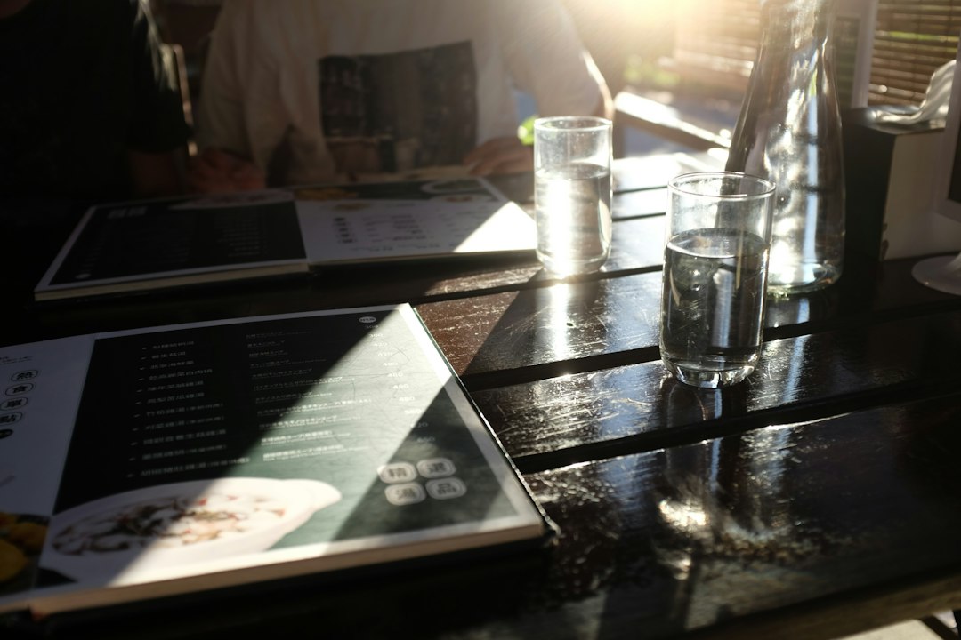 Two menus and glasses on a sunlit wooden table