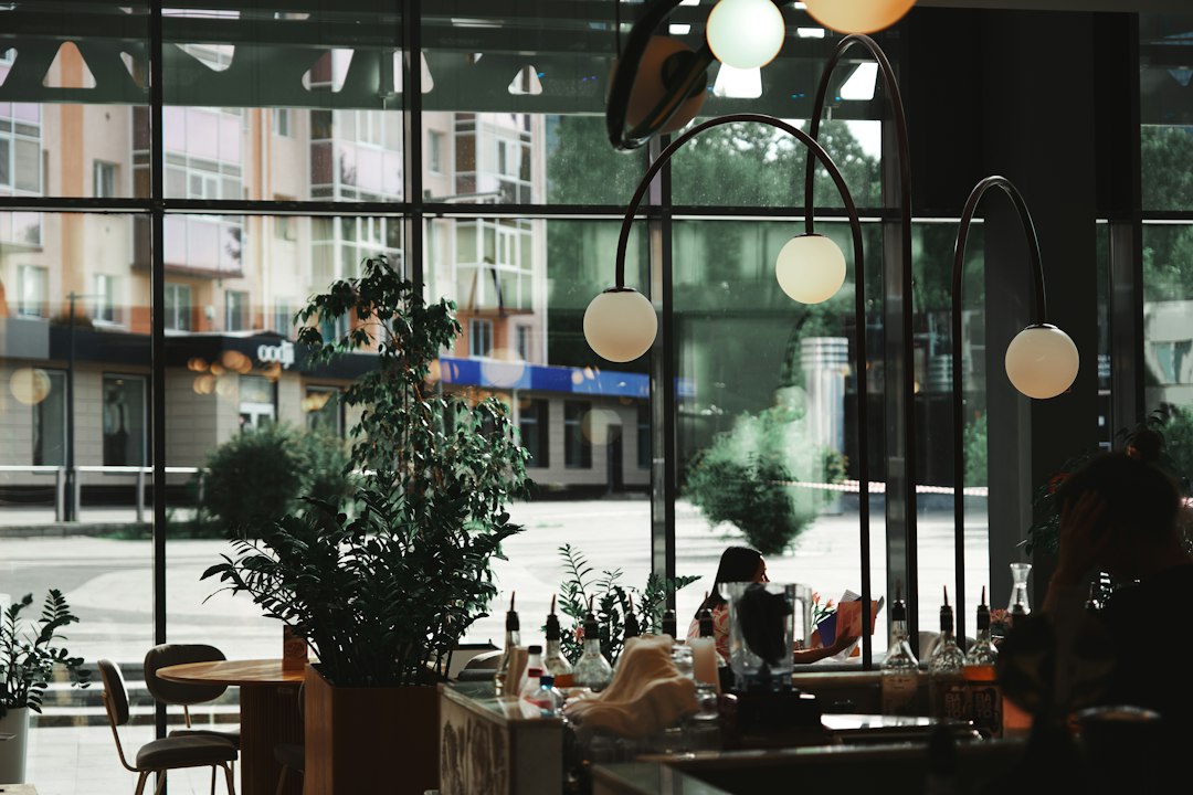 Relaxed cafe interior with plants, modern lights, and street view
