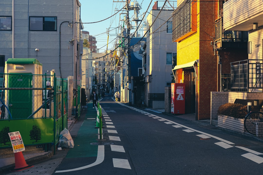 A narrow street in Tokyo with overhead power lines and a red vending machine