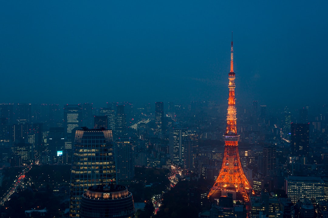 Tokyo Tower glowing orange above the dark blue cityscape of Minato City, Japan